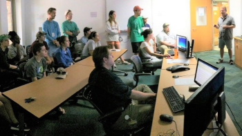 Students from College of Charleston (standing left) with Southeast Deep Coral Initiative Lead Scientist Peter Etnoyer (standing right) in Charleston’s “pop-up” Exploration Command Center during a NOAA Ship Okeanos Explorer watch party at Hollings Marine Laboratory. Credit: Bob Podolsky/College of Charleston.